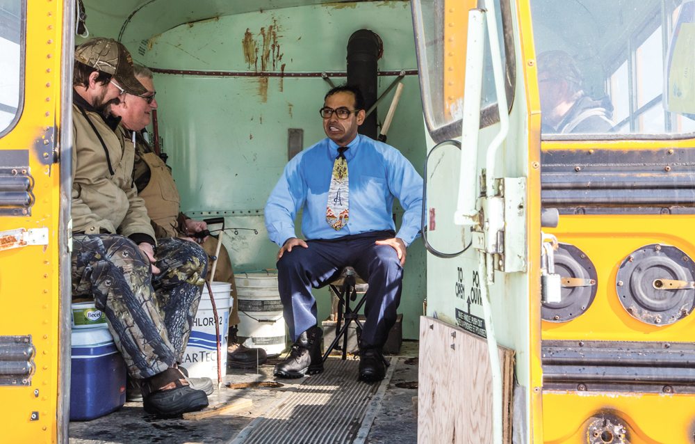 Shaun Majumder of CBC sketch comedy show “This Hour Has 22 Minutes” chats it up with Victor Boulet of Dunrea and Ken Shackel of Killarney in Boulet’s converted 1960s-era school bus. Majumder was in character for a sketch on Canadian winter pastimes.