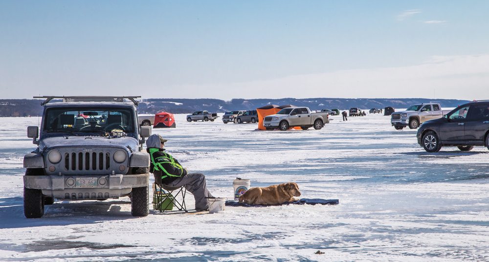 Wallace Stewart of Belmont waits for a strike while Trapper suns himself on Pelican Lake along with 885 other fishermen March 3.