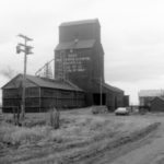The railway siding of Dand, about 10 miles north of Deloraine, was established in 1913 after the CPR laid tracks in the area. The first grain elevator was built later that year by the Dominion Elevator Company. It was sold to the Canadian Consolidated Grain Company in 1928, the same year that Manitoba Pool built a 40,000-bushel elevator nearby. In addition to two grain elevators, at its height Dand consisted of a train station, general store, garage, church, school and teacherage, and a handful of houses. A 30,000-bushel balloon annex, visible in this photo from the 1970s, was built beside the Pool elevator in 1940. The Consolidated elevator was destroyed by fire in fall 1950. The Pool elevator closed in December 1974 and was later demolished. Today, a lonely church still stands at Dand.