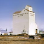 United Grain Growers built its first elevator at Deloraine in 1960, on the site of a former flour mill and power plant. The unusual-looking design was one of the earliest examples of “composite style” in which the elevator and annex were combined as a single, solid crib. The capacity when it opened on December 12, 1960 was 105,000 bushels but it was expanded with a 100,000-bushel crib annex in June 1976. Operation was taken over by Agricore United (now Viterra) in 2001 but it was closed in 2006 and demolished in mid-2010. The company’s other elevator, built west of town in 1973-74, was closed in 2002 and is now in private hands.