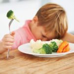 young boy eating vegetables reluctantly