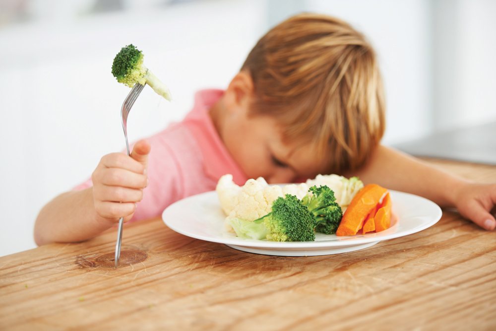 young boy eating vegetables reluctantly