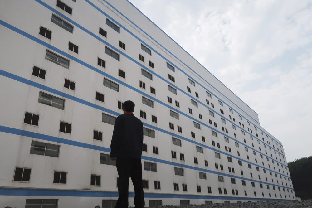 A worker outside a seven-storey pig building of Guangxi Yangxiang’s farm at Yaji Mountain Forest Park in Guangxi province, China, March 21, 2018.