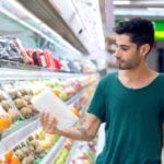 Young man choosing oranges in the supermarket