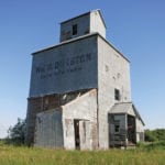A small wooden elevator in the RM of Dauphin, three miles north of Riding Mountain National Park, was built by local farmer William Durston in 1917. Born in England in 1871, Durston came to Canada at the age of three and moved with his family to this area in 1889. He was the first farmer in the region to use a combine to harvest his crops and one of the first to grow legumes.
The elevator is not in use and portions have fallen in the past few years.