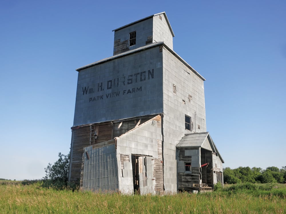 A small wooden elevator in the RM of Dauphin, three miles north of Riding Mountain National Park, was built by local farmer William Durston in 1917. Born in England in 1871, Durston came to Canada at the age of three and moved with his family to this area in 1889. He was the first farmer in the region to use a combine to harvest his crops and one of the first to grow legumes.  The elevator is not in use and portions have fallen in the past few years.