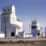 Beausejour had three wooden elevators (or four, depending how you count) when this photo was taken in 1962. The nearest was Pool B, built for Lake of the Woods Milling and sold to Manitoba Pool in 1959. Closed in 1994, it was demolished in 2002. One (or two) elevators in the middle shared a common driveshed. The older, smaller elevator was built in 1921 for the Dominion Elevator Company and was bought by UGG in 1959. The second, larger elevator was moved here by UGG. Both were closed in 1996 and demolished. At the far end was Pool A, dating from 1954 and modernized in 1981. The last to go, it was demolished in 2012. Beausejour will regain an elevator when the former Pool elevator at nearby Tyndall is moved to the local museum in 2020.
