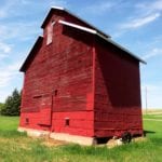 A small wooden-crib elevator in the Municipality of Norfolk Treherne, similar in design to Manitoba’s oldest elevator, at Elva, was built in 1901 by Irish immigrant William Twiss Grogan and his family. Local lore holds that it was built using lumber sawed from logs salvaged from a log-jam in the nearby Assiniboine River. It had four full-size bins and two half-bins. Sold to neighbour Alex Dobbin along with the surrounding land in 1911, the structure (seen here in May 2018) remains in good repair. It contains the original leg and is still used for grain storage by Dobbin’s descendants.