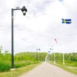 Flags from other countries, provinces and territories top Minnedosa's dam, alongside a walking path and historical interpretive signs.