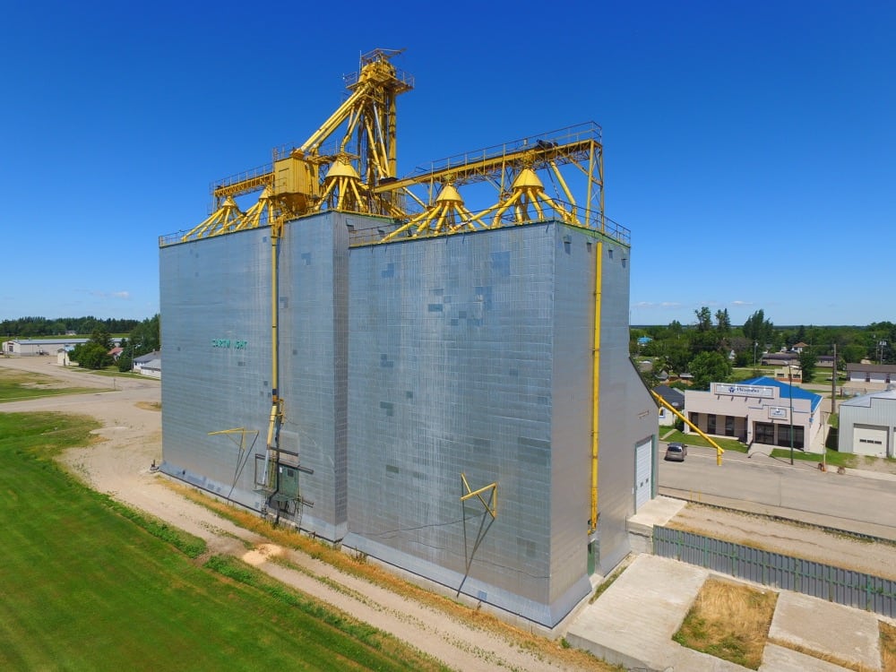 In 1981, Manitoba Pool built a 60,000-bushel crib annex on the west side of its 54-year-old elevator at Cartwright. Then, between October 1986 and December 1987, it constructed a 145,000-bushel composite-style (elevator and annex in a single crib) structure on the west side of the earlier annex (on the right in this 2018 photo) and demolished the old elevator on the east end. The facility was opened officially in April 1988. Closed by Agricore in July 2001 and put up for sale, the elevator was purchased by the Willow Creek Hutterite Colony which also rents out storage space to other farmers. The adjacent railway line was abandoned in May 2008.  
