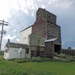 The former Manitoba Pool elevator at Lyleton was built in 1928. In 1967, a temporary annex dating from 1952 was replaced by a new metal-clad annex that increased the facility’s total capacity to 128,000 bushels. In April 1976, swollen waters of the Souris River washed out a railway bridge between Lyleton and Waskada. The CPR, which wanted to abandon the line to Lyleton, decided not to replace the bridge. Without a railway connection to the outside world, the elevator closed in December 1976 and the line was formally abandoned in December 1977. The elevator, seen in this photo from July 2016, was sold into private hands.