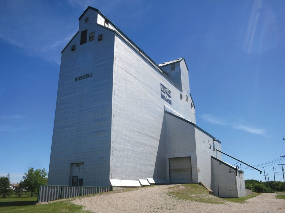 On March 5, 1974, the Manitoba Pool elevator and two annexes at Russell were destroyed by fire, along with 90,000 bushels of wheat. Construction of a replacement began within three months and, on January 30, 1975, a 170,000-bushel composite-style elevator (with elevator and annex combined into a single unit) was opened officially. Closed by Agricore in 2001 and sold to local interests, the off-track facility, seen here in June 2018, remains in use for private grain storage.