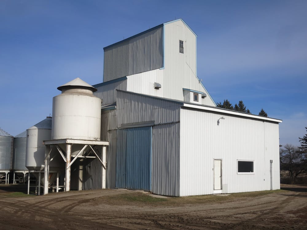 This seed-cleaning plant about five miles southeast of Notre Dame de Lourdes hardly looks like the elevator that lies at its core. Built by Federal Grain in 1936, to replace an elevator destroyed by fire in September 1935, it was closed in 1964 and sold to Gabriel Durand the following year. He removed a top portion of the crib to make it easier to move the nine miles to his farm then rebuilt the roof but not as high as the original. His son Marc continues to run the plant.
