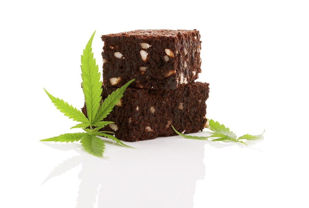 Delicious cannabis brownie with marijuana leaf isolated on white background.