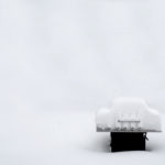 Snow covered outdoor grill during a winter snowstorm frozen cold bar-be-que white-out background type space