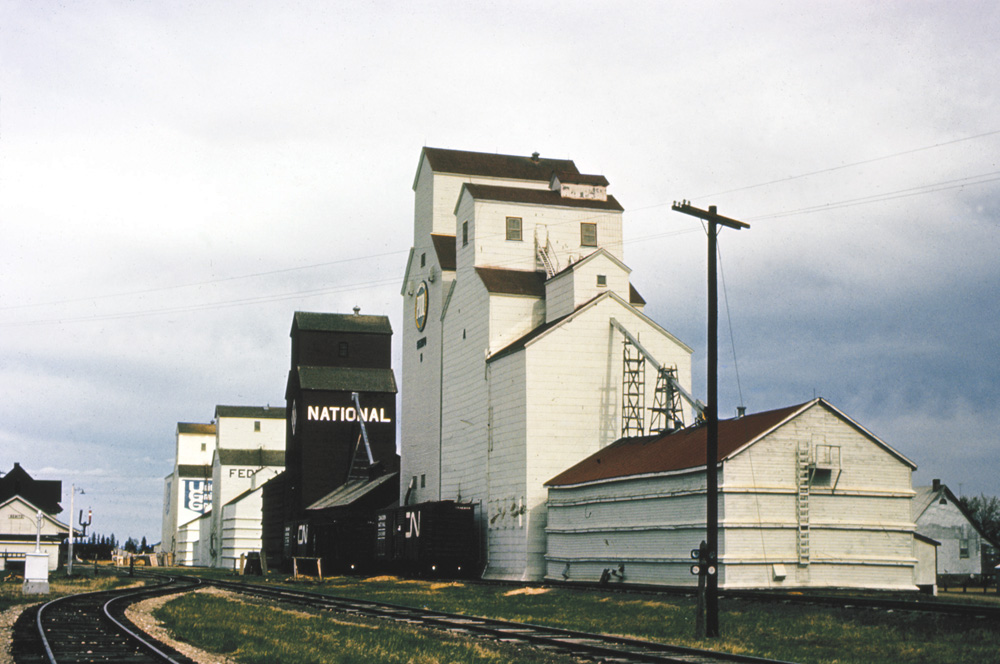 Benito had four elevators when this photo was taken in 1971. The United Grain Growers facility in the background dated from 1937. It was closed in 1997. The Federal elevator next to it was built in 1929 by Searle Grain, merged into Federal in 1966, and sold to Pool in 1972. It closed in 1983. The National elevator was built in 1912 by the British America Elevator Company, which merged into National in 1940 then sold to Federal in 1969 and to Pool in 1972. It closed in 1980. The Manitoba Pool elevator in the foreground was built in 1952 alongside two older, smaller elevators. Renovations in 1976 entailed replacement of the oldsters with a modern crib annex. This last elevator in town was closed in January 2002 and demolished later that year.