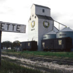 The original Manitoba Pool elevator at Ninette burst open and collapsed in September 1967 and was replaced by one moved from nearby Hilton, acquired in trade from United Grain Growers. The relocated elevator was officially opened in December 1967, with the first unloading by John McKay, the last still-farming original member of the Ninette Pool Elevator Association. This photo of it dates from 1977. The elevator was closed in August 1987 and, despite efforts to save it, was demolished in late October 1988, with the debris burned at the local landfill.