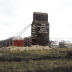 In 1965, the provincial government bought two elevators and annexes at Fortier, about 24 kilometres (15 miles) southeast of Portage la Prairie, from Manitoba Pool. The “A” elevator had been built by Pool in 1928 while the “B” elevator dated from 1913 and had been bought from Ogilvie Flour Mills in 1959. The government used the abandoned right-of-way for the CN railway line beside the elevators to expand the Trans-Canada Highway from two to four lanes. By the time of this 1973 photo, the former A elevator had been moved to a nearby Hutterite colony.