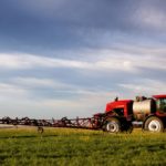 A high clearance sprayer on a field in a prairie landscape