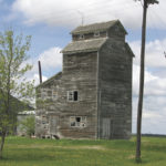 An elevator in the RM of Stanley was built in 1943 as a seed-cleaning plant for George G. Elias (1914-2012), on the former site of the Eichenfeld German School. A crew of 16 men built the state-of-the-art facility crib structure, which could process up to 1,000 bushels of grain each day, using 2x6 timbers at a cost of about $8,000. In 1946, Elias’s barley won first prize at the Royal Winter Fair in Brandon and, later that year, captured first prize in a national contest sponsored by the newly formed Barley Improvement Institute of Canada. It won the national award again in 1950 and Elias was proclaimed the “Barley King” of Manitoba. An active member of the Canadian Seed Growers Association for over 65 years, he continued to sell certified seed throughout Canada until retirement in 2000. The elevator was moved to the Pembina Threshermen’s Museum in February 2015 where it houses grain- milling demonstrations and a display of Elias family history.