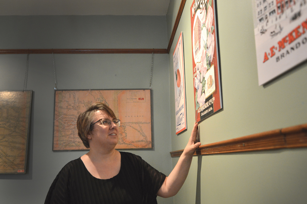 Daly House Museum curator Eileen Trott shows off colourful reproductions of historic McKenzie Seed catalogue covers.