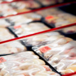 Packaged chicken legs in store refrigerator.