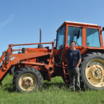 Devin Pouteau with his trusty, Soviet-era Belarus tractor on his farm near Sanford.