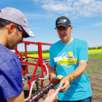 Spray specialist Tom Wolf of Sprayers 101 helps demonstrate the WEEDit system this July, using water- sensitive pads laid on the ground to show droplet placement.