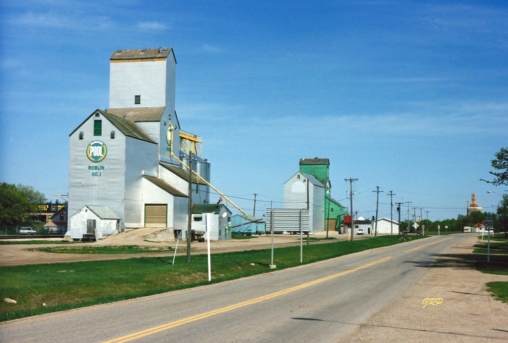 Roblin Pool: The first Pool elevator in Manitoba was built in 1925 at Roblin. In 1968, an 18-bin crib annex was built beside it to replace a balloon annex. Demolished in May 1986, the Pool C elevator (built in 1951 next to Pool B) was moved to this site, beside the crib annex, and fully renovated with a digital scale and twin legs. Two steel tanks were added in the late 1980s or early 1990s. It was the last wooden elevator in Roblin, the right elevator belonging to Cargill having been demolished in July 1998. Pool No. 1 was demolished in August 1999 following the opening of a concrete elevator built nearby as a joint project between Manitoba Pool and Pioneer Grain.