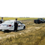 RCMP officers approach a truck on a farm property.
