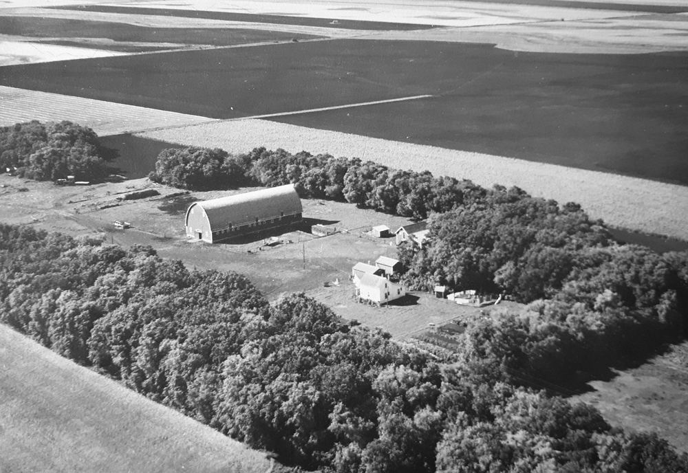 This old black and white aerial photo shows our farmyard four generations ago. My husband’s great-grandparents settled here in 1926, a second move after immigrating from Scotland in 1922. They wanted a farm with trees, good drinking water and soil without stones. This site fits the criteria to make living and farming here better. Much has changed since but reminders of our past remain with some of the buildings repurposed or repaired. Old steel wheels and pieces of harrow bar grace my flowerbeds and garden. Picture frames have been made from discarded barn windows. Our kitchen table and chairs are crafted from wooden barn beams. It’s important to remember our history and to look back with gratitude on the hard work, determination and resilience of our ancestors. It ensured we could farm, make a life and a living here.
