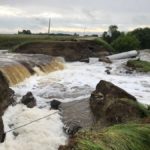 The same road falls prey to floodwater pressure by 8:30 a.m. June 30.