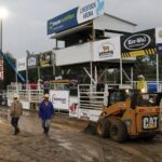 Organizers tried to drain water in front of the chutes before Saturday’s bull riding event.