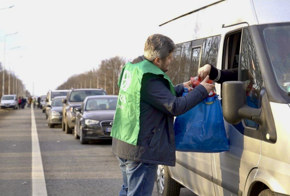 A worker with Foodgrains Bank partner ADRA gives food and supplies to cars waiting to cross into Romania.