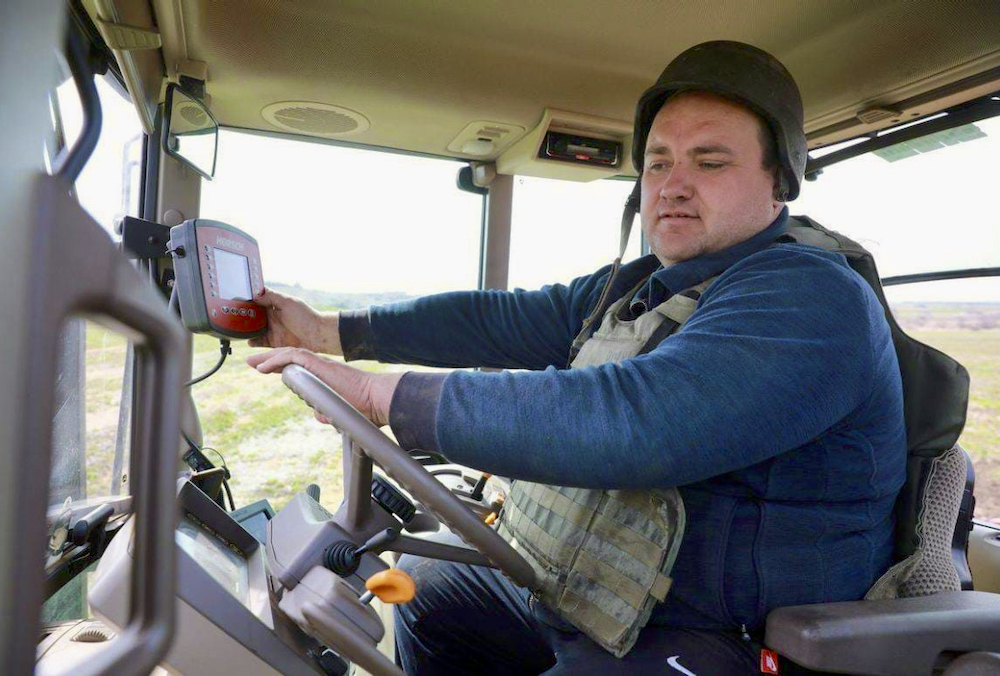 A Ukrainian farmer sows his fields wearing a military helmet and body armour.