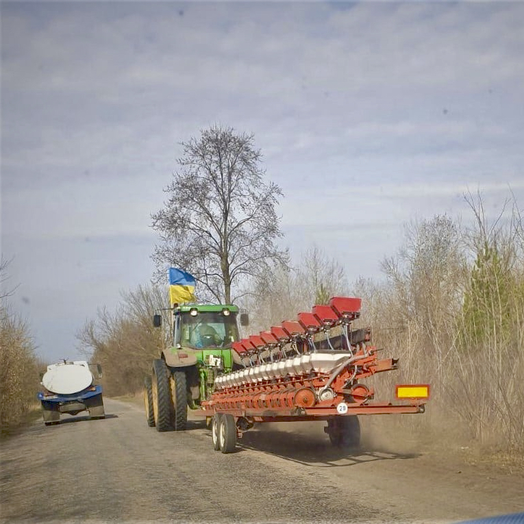 A farmer flies the flag of Ukraine while hauling his planter to the field.