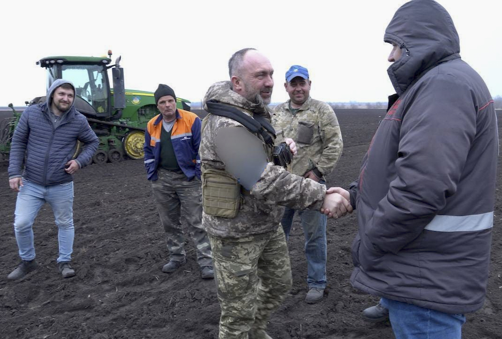 A soldier meets with Ukrainian farmers in the liberated fields of northern Ukraine.