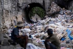 A man looks through piles of trash on a stream in Port-au-Prince, Haiti on Oct. 13, 2022. (Photo: Reuters/Ricardo Arduengo)