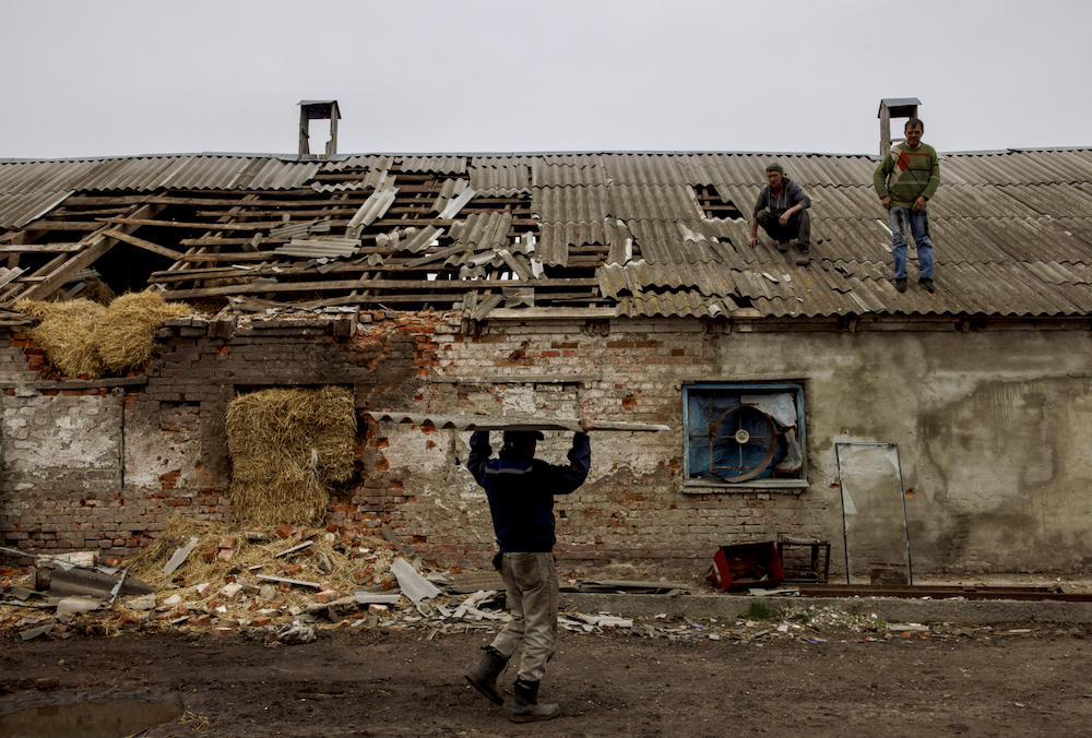 Workers repair the roof of a farm building that was damaged by a mortar, in the village of Malaya Rohan, as Russia's attack on Ukraine continues, in the Kharkiv region, Ukraine, April 9, 2022.