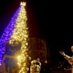 A woman sings a carol in front of a Christmas tree, amid Russia’s attack on Ukraine, at the Sofiyska Square in Kyiv, Ukraine, Dec. 19.