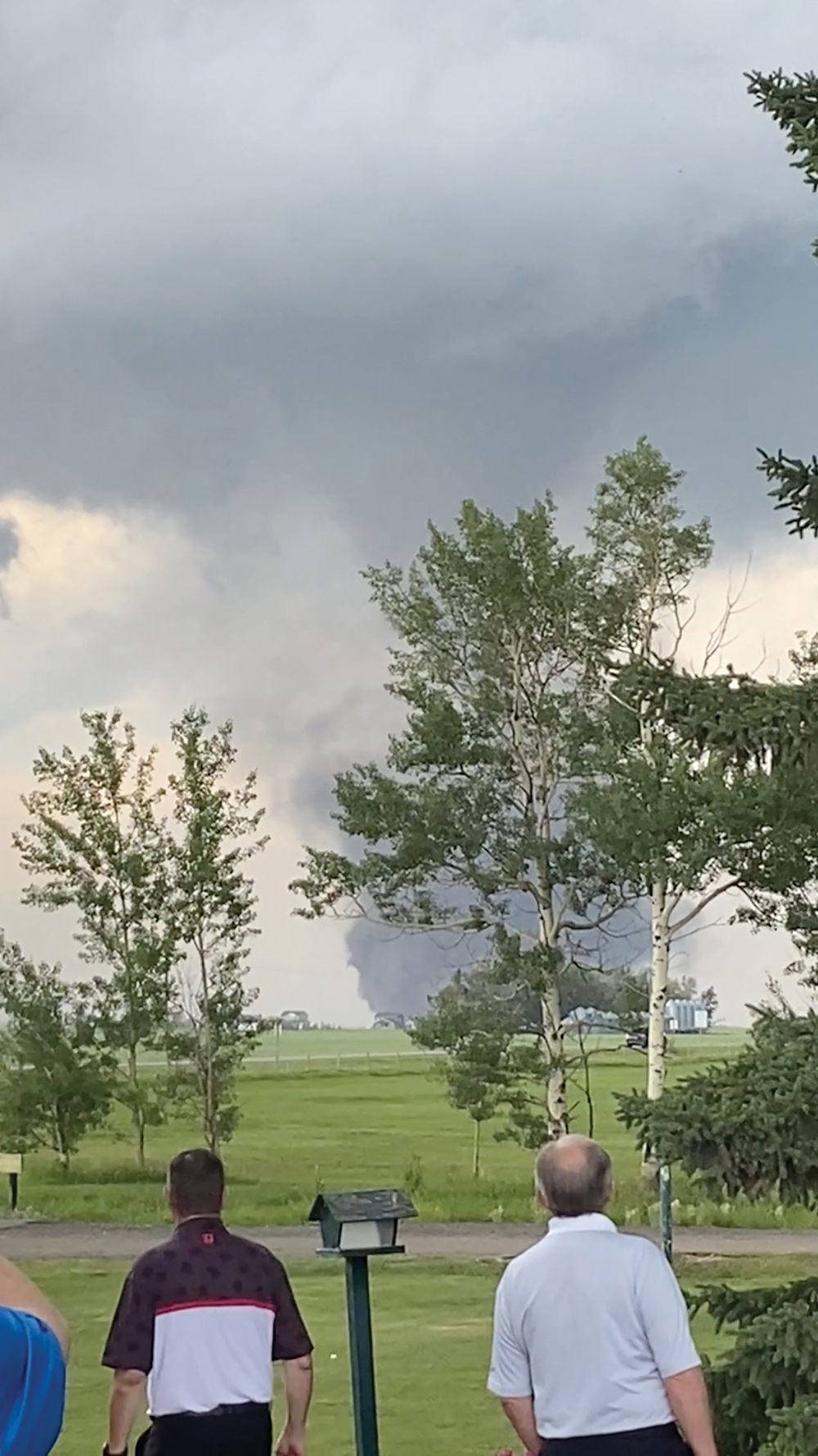 People watch as a tornado swirls near Carstairs, Alta.  on July 1 in a screengrab from a social media video.