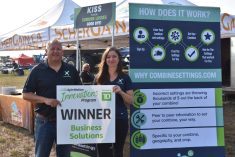 Trevor Scherman and Megan Madden hold the sign displayed in front of their ScherGain booth at Ag in Motion on July 20, 2023.  Photo: Braedyn Wozniak

