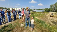 Kelsey Sunaert speaks with a tour group beside a now-empty irrigation reservoir built on his Deloraine-area farm.