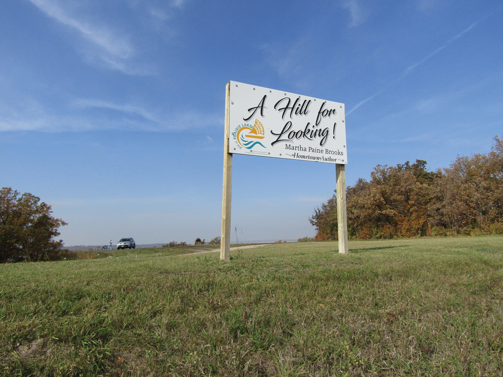 A sign referencing local author Martha Paine Brooks welcomes visitors to the viewpoint at Ninette, Man.