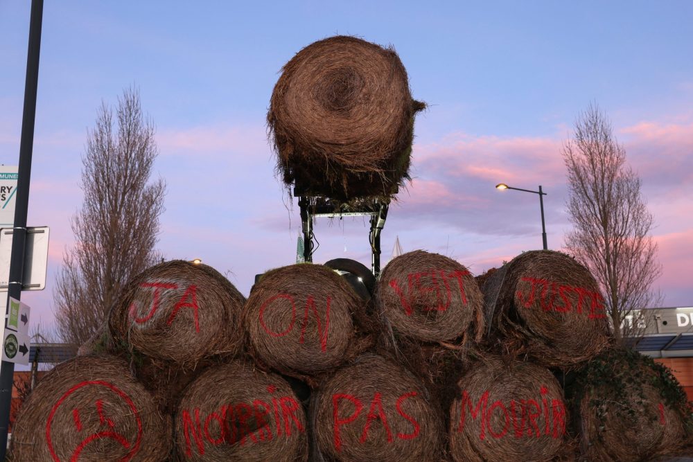 A hay bale is moved by a tractor over a pile to block a road, as French farmers protest over price pressures, taxes and green regulation, grievances shared by farmers across Europe, near Castelnaudary, in the south of France, January 23, 2024. The text on the hay bales reads: “JA” referring to “Jeunes Agriculteurs” (Young Farmers) and “We just want to feed, not die”. Photo: Reuters/Nacho Doce
