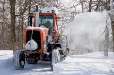 A farmer in south-central Manitoba blows snow after an April snowstorm in 2021.