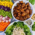 Chicken Teriyaki bowl ingredients, including chicken, radishes, sliced carrots and edamame beans.