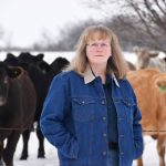 Dr. Cheryl Waldner standing in front of a herd of cattle.