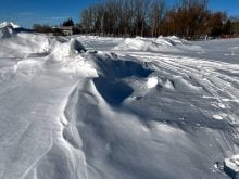 A snowmobile track cuts between deep drifts at Minnedosa Lake after a spring snow storm.