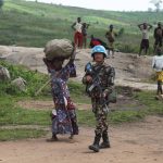 UN peacekeepers guard Congolese farmers working their fields
